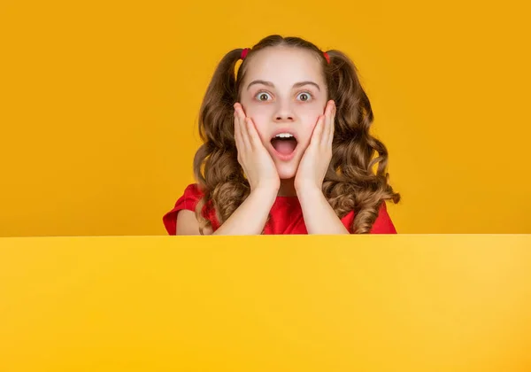 Shocked child behind blank yellow paper with copy space for advertisement — Φωτογραφία Αρχείου
