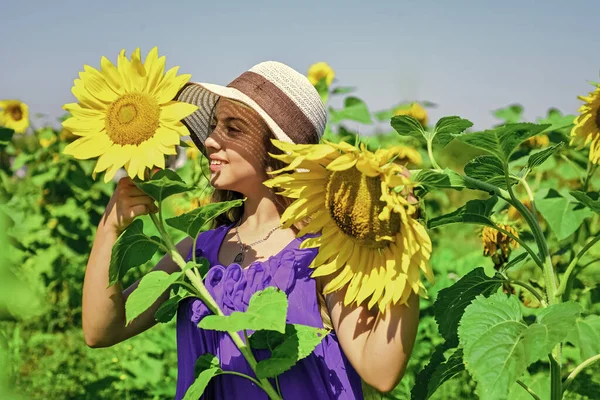 Χαρούμενη ημέρα των παιδιών. Παιδική ευτυχία. πορτρέτο του ευτυχισμένου παιδιού με όμορφο ηλιοτρόπιο. χαρούμενο παιδί με ψάθινο καπέλο ανάμεσα σε κίτρινα λουλούδια. μικρό κορίτσι σε καλοκαιρινό χωράφι με ηλιοτρόπια. Νέα άνθη — Φωτογραφία Αρχείου