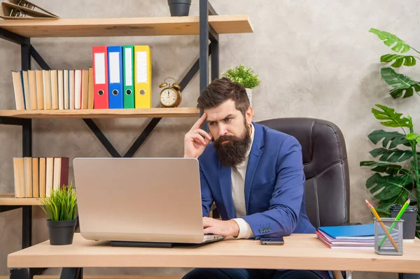Bir proje yürütüyorum. İşletme. İşyerinde düşünceli bir yönetici. Dizüstü bilgisayarda çalışan profesyonel bir adam.