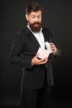 Smokinli, papyonlu, siyah arka planda, ödül kutusuyla büyülenmiş bir adam. özel selamlama.