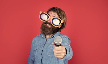 Beyaz tenli sakallı, şık saçlı, sanatsal gözlüklü, mikrofonlu, karaokeli