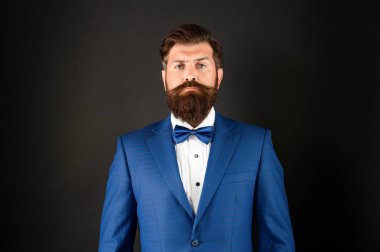 Mavi smokinli ciddi bir adam. Siyah arka planda resmi giyinen bir adam. erkek resmi moda