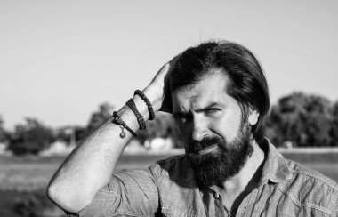 Harika bir tarzı var. Kendine güvenen ve yakışıklı bir adamın bahar portresi. Vahşi sakallı adam günlük gömlek ve güneş gözlüğü takıyor. Erkek yaz modası ve güzellik. Bıyıklı, vahşi, beyaz bir hippi.