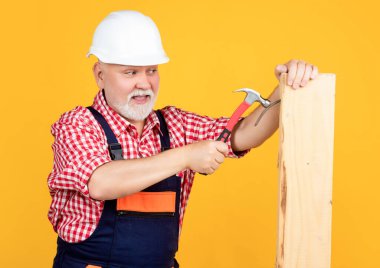 cheerful senior man woodworker in hard hat on yellow background