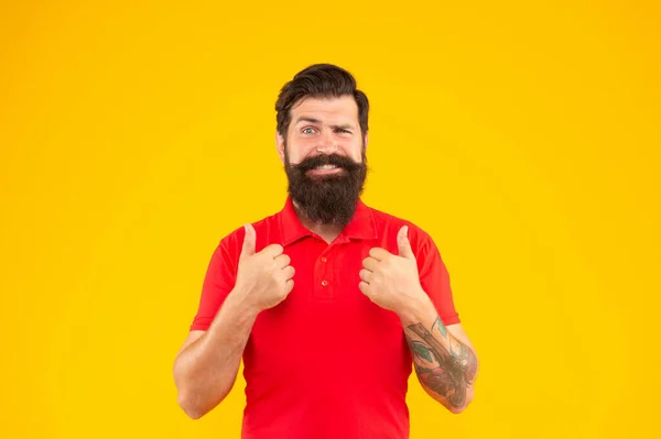 Homem barbudo feliz com bigode na tshirt mostrando polegar no fundo amarelo, mens beleza — Fotografia de Stock