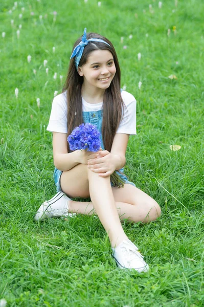 Positive girl sitting on grass with spring flowers — ストック写真