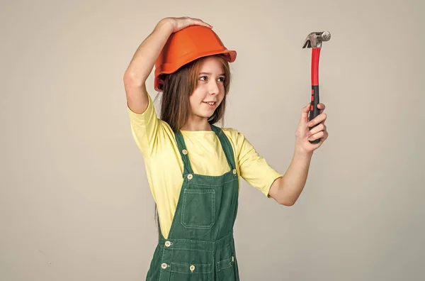 Девушка-работница в защитном шлеме и форме на сером фоне использовать молоток, работник — стоковое фото