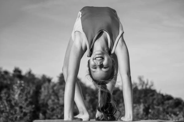 Happy and sporty. happy teen girl in handstand. kid has flexible body. child in sport clothes training. concept of stretching and warming up. childhood happiness. health and fitness. gymnastics — Stock Photo, Image
