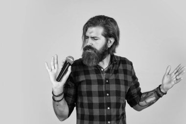 Müzik benim hayatım. Bıyıklı vahşi yakışıklı adam şarkı söylüyor. Olgun adam mikrofonda şarkı söylüyor. Karaoke. Sıradan moda stili şarkıcı. modern görünümlü sakallı hippi mikrofonlu.
