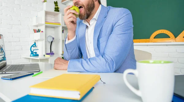 Школьный учитель в классе обедает с яблоком — стоковое фото
