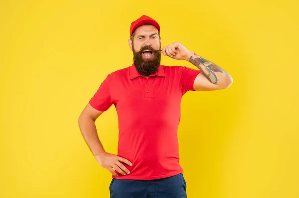 Felice uomo ammiccante in casual berretto rosso e maglietta turbinante baffi sfondo giallo, tuttofare — Foto Stock