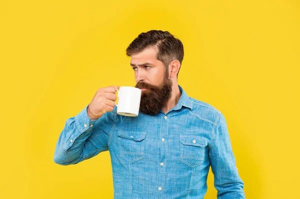 Homem caucasiano grave bebendo café de fundo amarelo caneca — Fotografia de Stock