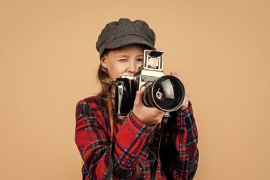 Retro fotoğraf makinesi olan genç kız modaya uygun şapka ve damalı ceket giyer, klasik fotoğrafçılık yapar.