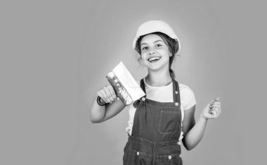 İş bittikten sonra. Gelecekteki mühendis. Mutlu çocuk spatula tamir aleti kullanıyor. İnşaat alanı. Çocuk mimar. İşçi Bayramı konsepti. Çocukluk gelişimi. Genç kız asistanı