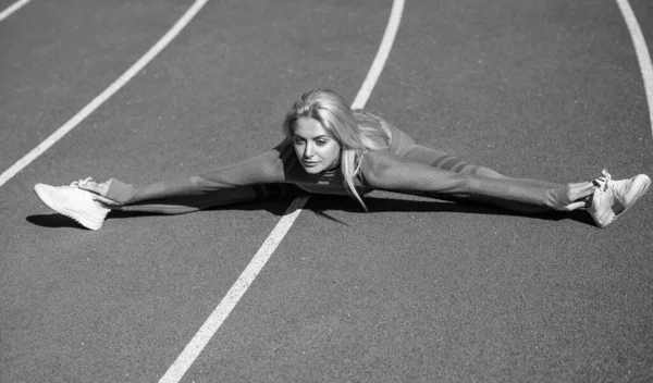 Atleta esportiva feminina em sportswear no estádio de aquecimento antes do treinamento de fitness, split stretching — Fotografia de Stock