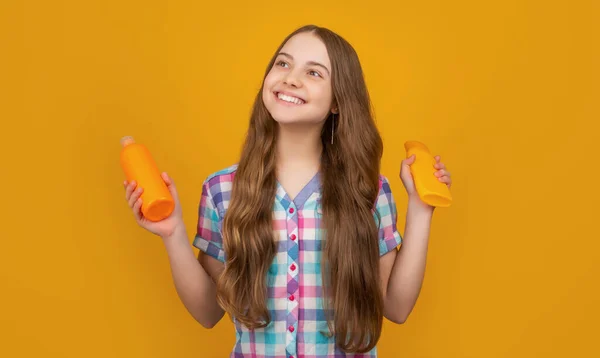 Glückliches Kind mit einer Flasche Haarspülung auf gelbem Hintergrund — Stockfoto