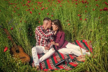 Gitarlı aşıklar çiçek tarlasında şarap içerler. Müzik. Birbirine aşık çiftler. Gelincik tarlasında kadın ve erkek.