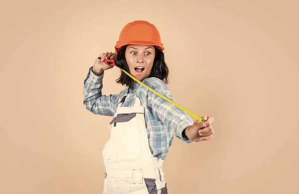 Express yourself. girl builder in hard hat on construction site. engineer hold tape measure. young female worker on beige background. repair and renovation. woman wear protective helmet — Stock Photo, Image
