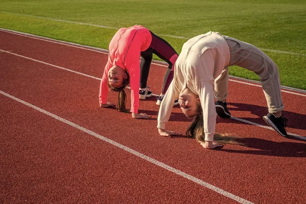 Chicas flexibles gimnastas de pie en posición de cangrejo en pista de atletismo, flexibilidad — Foto de Stock