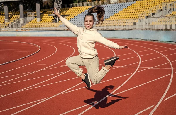 Chica energética niño saltar en atletismo pista educación física al aire libre, deporte — Foto de Stock