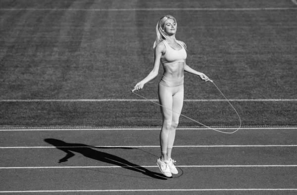 より高くジャンプする。陸上競技の女子はジャンプロープを使う。女性アスリートはスポーツワークアウトをジャンプします。ロープを飛ばしてトレーナーやコーチのトレーニングをします。健康的でスポーティ。スポーツウェアのセクシーなフィットネス女性 — ストック写真
