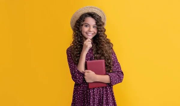 Lächelndes Kind mit krauses Haar liest Buch auf gelbem Hintergrund — Stockfoto