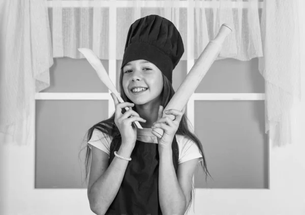 Limpeza e ajuda em casa. desenvolvimento infantil. menina pequena assar na cozinha. chef criança cozinhar com rolo de pino e colher de madeira. criança preparar comida saudável em casa e vestindo uniforme de cozinheiro — Fotografia de Stock