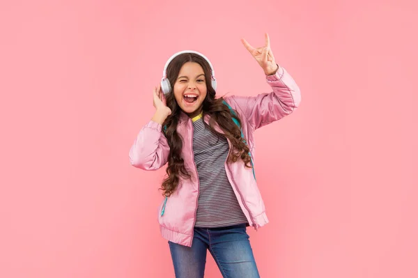 Chica adolescente alegre con mochila con auriculares en el fondo rosa, la educación —  Fotos de Stock