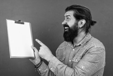 good looking hipster with beard and moustache showing document paper for making notes, copy space, ad.
