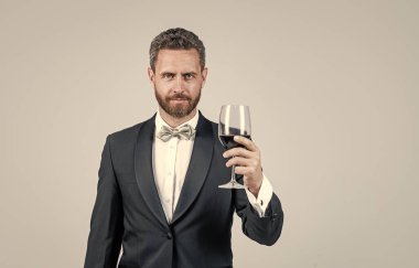 Yakışıklı smokinli adam arkasında kırmızı şarap kadehiyle tezahürat yapıyor. Hediye kutusu, fotokopi odası, şarap garsonu..