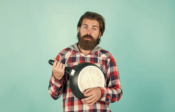 funny cooking. man holding frying pan.. male chef kitchener cooking. hipster checkered shirt for bearded guy cook. unshaven brutal man with kitchen utensil. household goods. friendly shop assistant.
