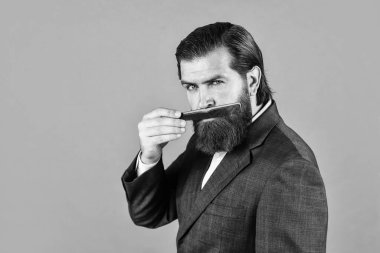 Berber dükkanında saç ve sakal tımar etme ustası. Kuaför saç stili yapar. Hipster 'ın moda portresi. Uzun siyah sakallı ve bıyıklı yakışıklı adam saç fırçası tutuyor. Boşluğu kopyala.