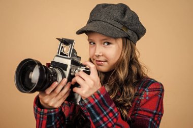 Paris 'li çocuk fotoğraf çekiyor. Fransız bereli şık çocuk retro kamera kullanıyor. Klasik dijital teknoloji. fotoğraf hobisi. Kareli ceketli genç kız fotoğrafçı. Mutlu çocukluk. güzellik ve moda.