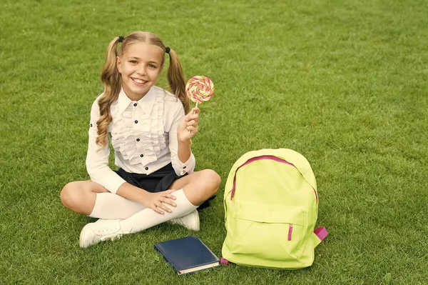 Šťastná Dívka Dítě Školní Uniformě Držet Sladké Lízátko Sedí Zelené — Stock fotografie