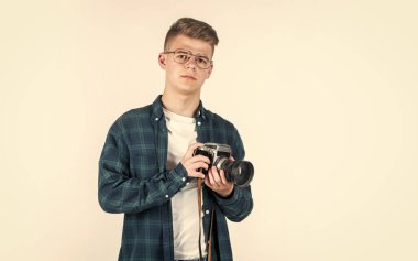 Mutlu çocukluk. Şık çocuk fotoğraf çekiyor. Kameralı modaya uygun bir genç. Çocuk fotoğrafçısı. Gözlüklü çocuk. Hobi. Genç çocuk retro kamera kullanıyor. Fotoğrafçılık. Boşluğu kopyala.