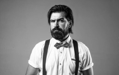 Şarap garsonu. Saçları taranmış gerçek bir beyefendi. Erkek güzellik ve moda. Berber dükkanı konsepti. Smokinli ve pantolon askılı sakallı adam. Seçkin iş adamı resmi etkinlikte papyon takar. Berber dükkanı servisi.