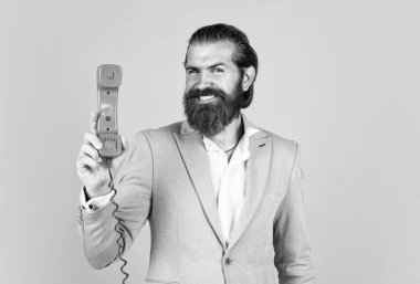 Ceketli, modaya uygun saç stili olan yakışıklı beyaz iş adamı klasik telefonla konuşuyor, dijital çağda..