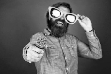 Bunu dene. Mutlu gülümseyen olgun adam. Sakallı adam mikrofonda şarkı söylüyor. Vahşi Kafkas hipster etkinlik yöneticisi. Komik parti gözlükleri. Karaoke ve müzik. Mikrofonlu erkek hoparlör. vokal.