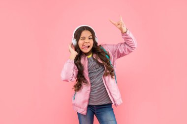 Müzik dinle. Kablosuz kulaklık cihazı aksesuarı. Yeni teknoloji. Çocukluk gelişimi. Modern kulaklıklı, sırt çantalı bir çocuk. Online eğitim. Okula dönüyorum. Kulaklıklı komik genç kız..