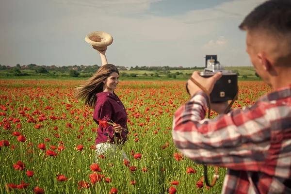 couple in love making photo. man with camera and woman in poppy field. summer flower meadow. romantic couple among poppies. love and romance. opium. spring countryside. lovers in flower field.