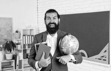 Sakallı ve bıyıklı olgun bir coğrafyacı. Okulda takım elbise giyiyor, eğitim görüyor..