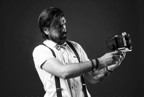 photo shooting. retro man in suspenders and bow tie. confident elegant photographer hold classical camera. journalist with vintage photo camera. formal party reporter. old fashioned bearded hipster.