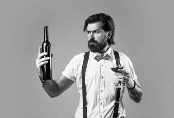 wine delivery service. drinking wine glass. bearded man in suspenders drink red wine. elegant businessman wear bow tie for formal event. sommelier tasting alcohol. bartender. stylish male barman.