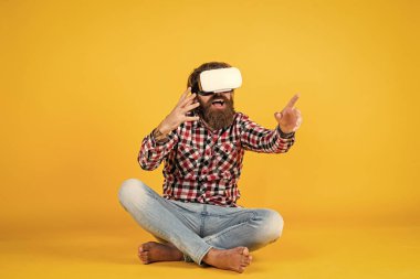Yeni gerçeklik burada. Mutlu gelecek. Adam kablosuz internet gözlüğü takıyor. VR kulaklıklı adam. Sakallı hippi modern teknoloji kullanır. Dijital gelecek ve yenilik. Sanal gerçeklik gözlüğü takan acımasız bir adam..