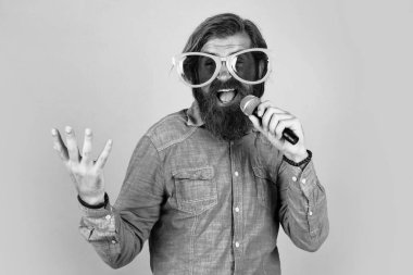 Yüksek sesle konuş. Mikrofonlu erkek hoparlör. Sesli. Mutlu gülümseyen olgun adam. Sakallı adam mikrofonda şarkı söylüyor. Vahşi Kafkas hipster etkinlik yöneticisi. Komik parti gözlükleri. karaoke ve müzik.