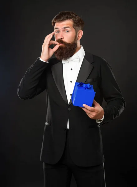 man in tuxedo bow tie formalwear on black background with box for mens day. perfect or excellent gesture. ok.