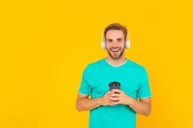 Okula dönüyorum. Kulaklıklı genç adam. Müzik aşığı. Müzik dinle. Kablosuz cihaz aksesuarı. Yeni teknoloji. Modern kulaklıklı, kahve fincanı olan mutlu bir adam. çevrimiçi eğitim.