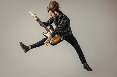 duygusal sakallı rock müzisyeni elektro gitar çalıyor deri ceketle ve zıplayarak, gitarist.