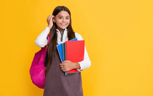 黄色の背景に学校のバックパックとノートを持つ幸せな子供 — ストック写真