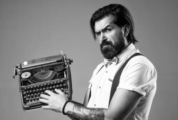 he is a writer. brutal guy in bow tie. elegant male typist. handsome hipster use technology in modern life. mature reporter or journalist. bearded man in suspenders with retro typewriter.